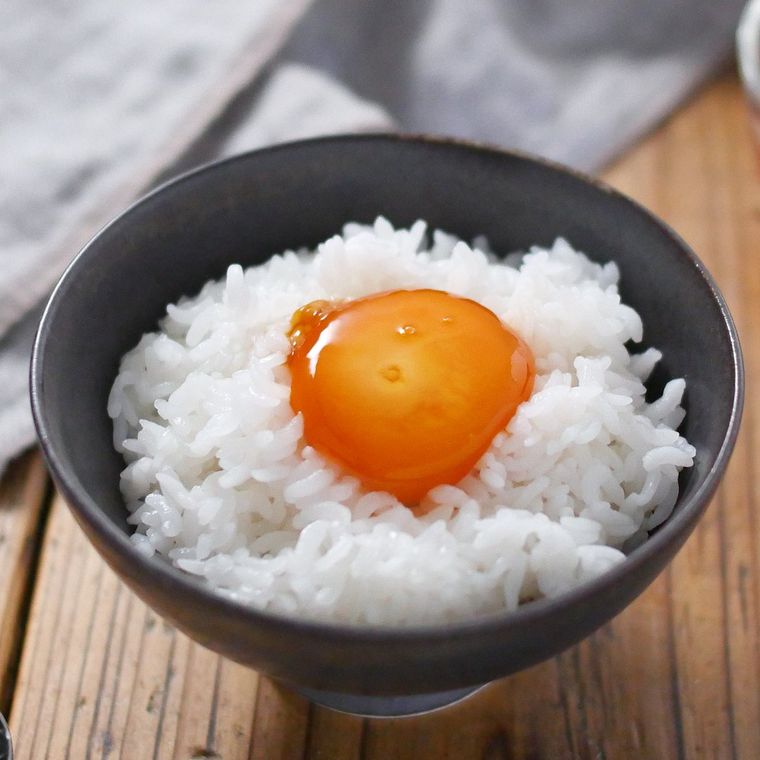 黒いお茶碗によそった、卵黄のしょうゆ漬けをのせたご飯