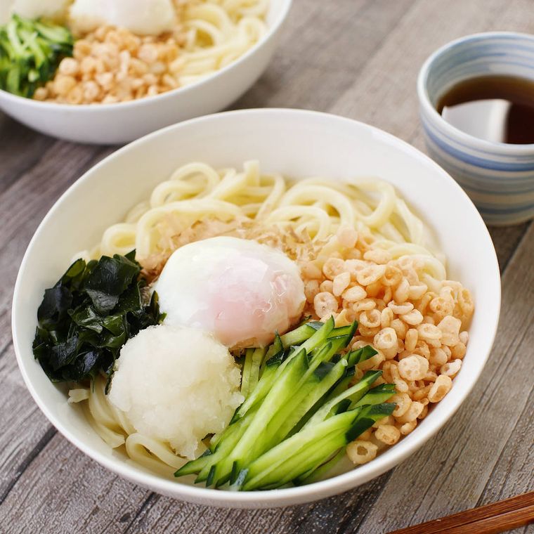 白い丼鉢に盛りつけられた温泉卵トッピングの冷やしたぬきうどん