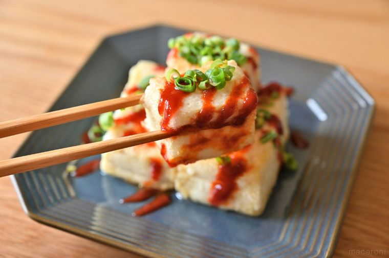 シラチャーソースをかけた豆腐ステーキを箸でつかんでいる