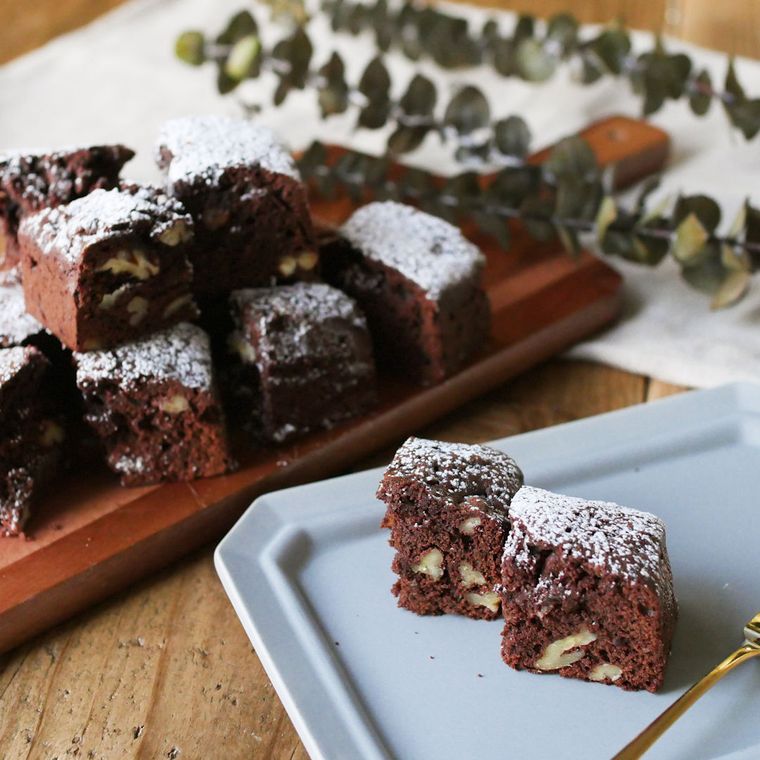 青いお皿と木製のカッティングボードにのった、オレンジピール入りのブラウニー