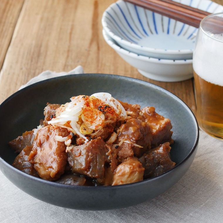 灰緑色の深皿に盛りつけられているこんにゃくと厚揚げのどて煮