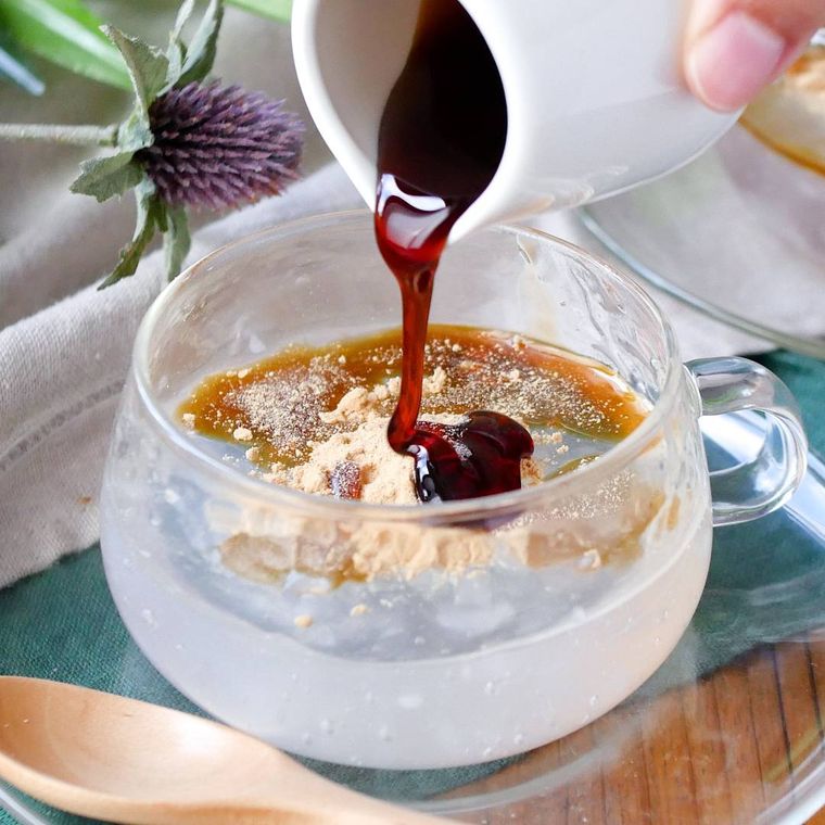 マグカップに入っているわらび餅に黒蜜をかけている様子