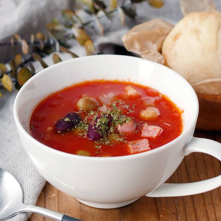 持ち手がついた白いスープカップに入ったチリトマトスープ