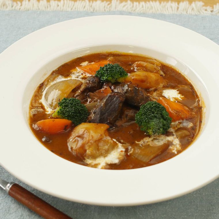 白い皿に盛り付けられたじゃがいもとにんじんのビーフシチュー