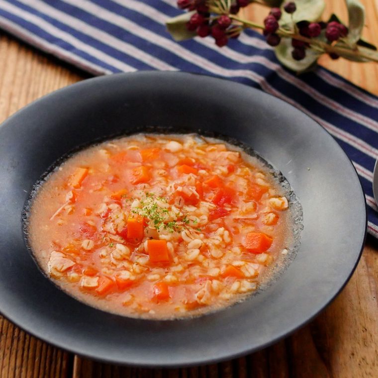 黒い皿に盛り付けられた押し麦のトマトスープ