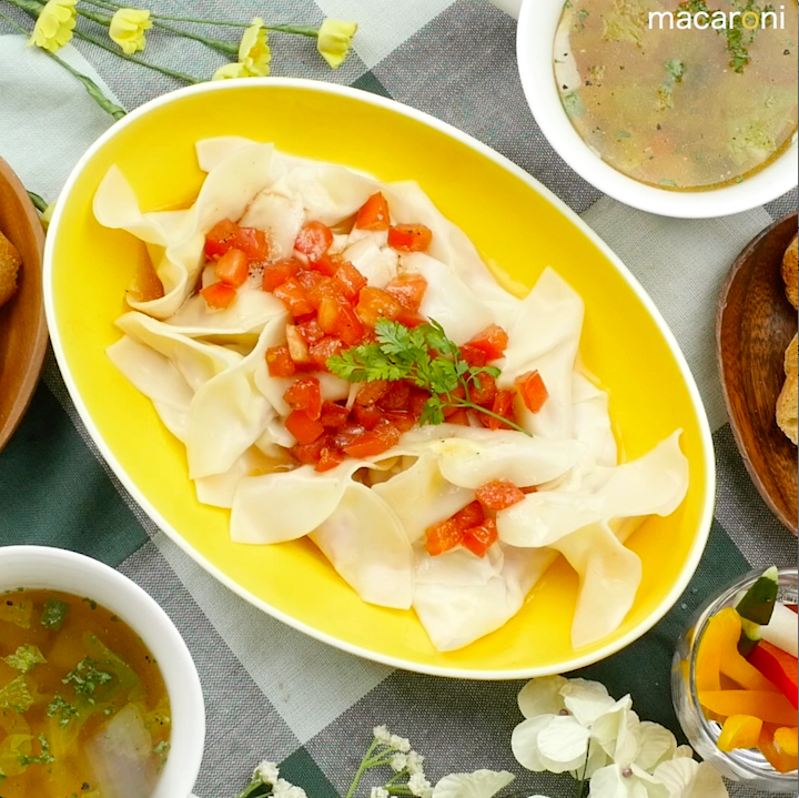 黄色い長皿に盛りつけられた生ハム入り水餃子のトマトポン酢だれ
