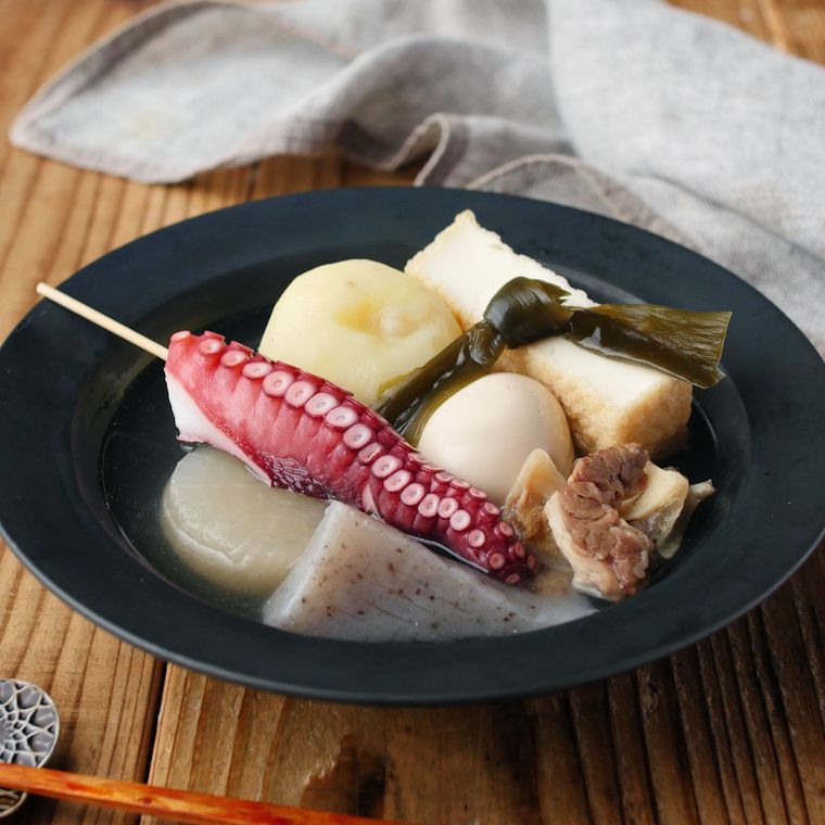 黒い皿に盛りつけられた牛すじ肉やこんにゃく、大根などのおでん