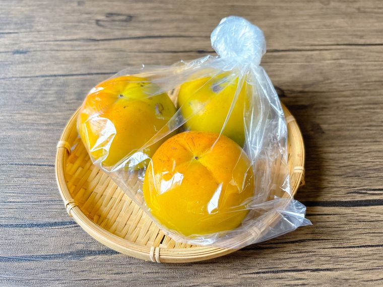 ザルにおかれたポリ袋に入った柿