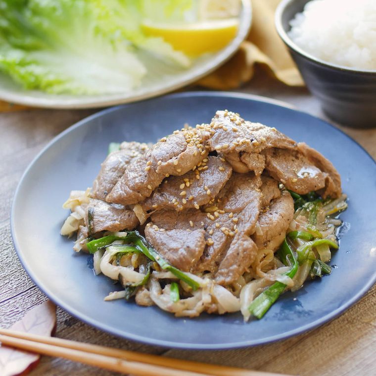 青い皿に盛りつけられているラム肉薄切りや玉ねぎなどの炒め物