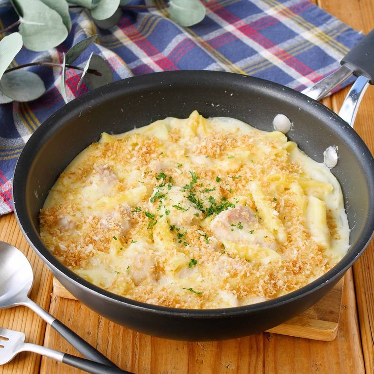 焚き火で作ったチキンとマカロニのフライパングラタンがフライパンに入れられチーズがとろけて盛り付けられているところ