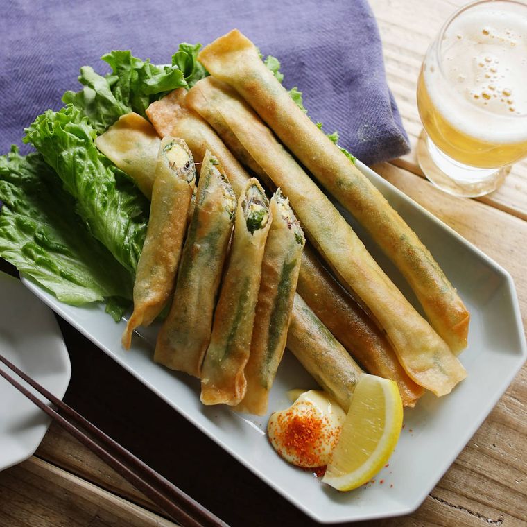 皿に盛り付けられたししゃもの揚げ春巻きと野菜などのつけ合わせ