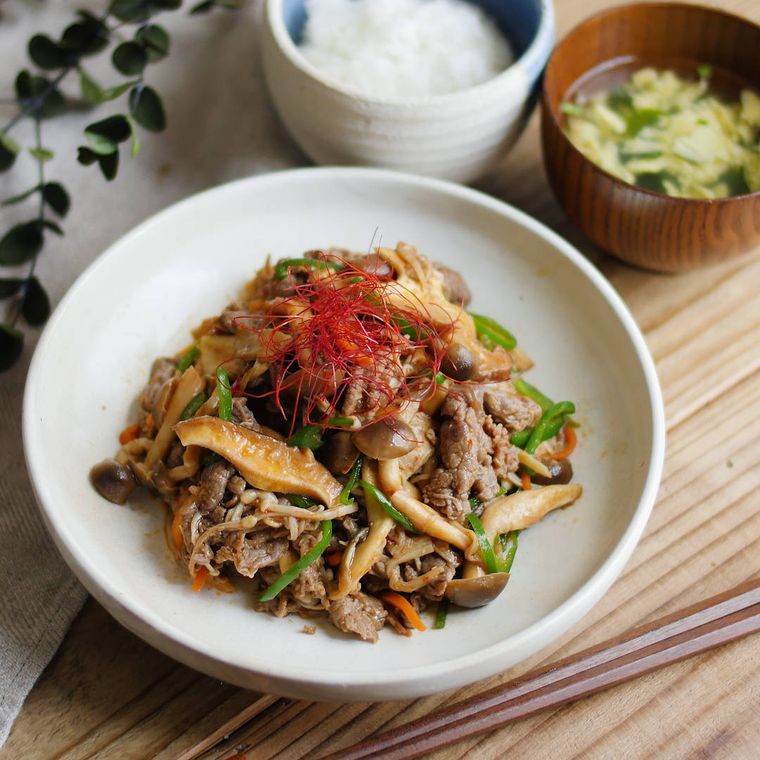 白い丸皿にたっぷりきのこのプルコギが盛られている。奥にはご飯と味噌汁が置いてある