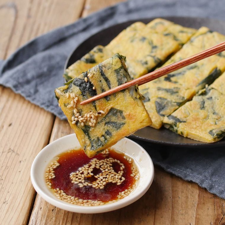 黒い丸皿にわかめとしらすの和風チヂミが盛られている