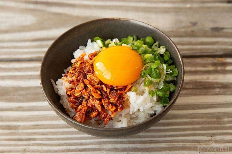 黒色の茶碗に盛られた食べるラー油と青ねぎのTKG