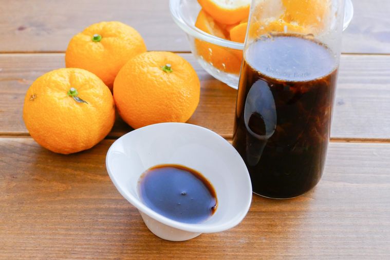ゆずとポン酢が入っている小皿と保存容器が並ぶ木製テーブル