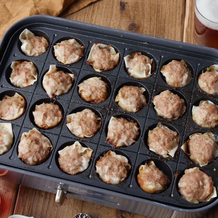 グレーのたこ焼きプレートで焼かれているシュウマイ