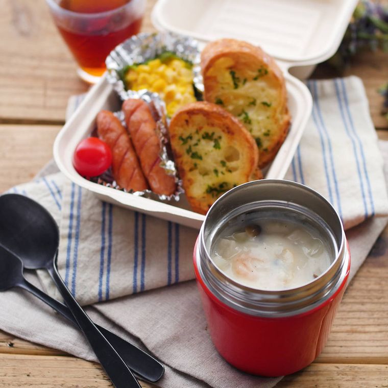 赤いスープジャーに入ったシーフードシチューと、白いボックスに入ったガーリックトーストとおかず