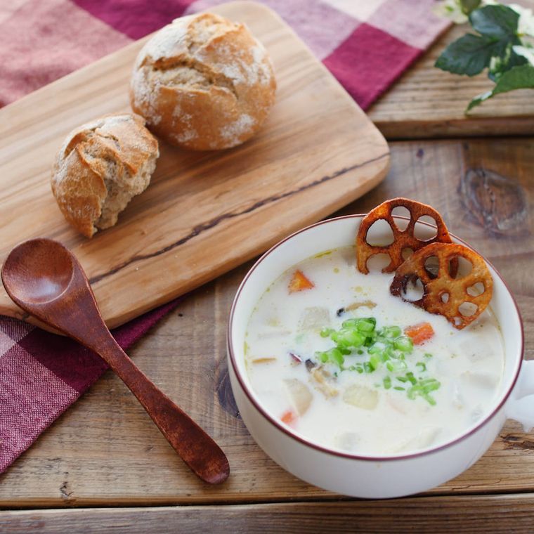 縁取りのある白いカップに盛りつけられた根菜のクラムチャウダー