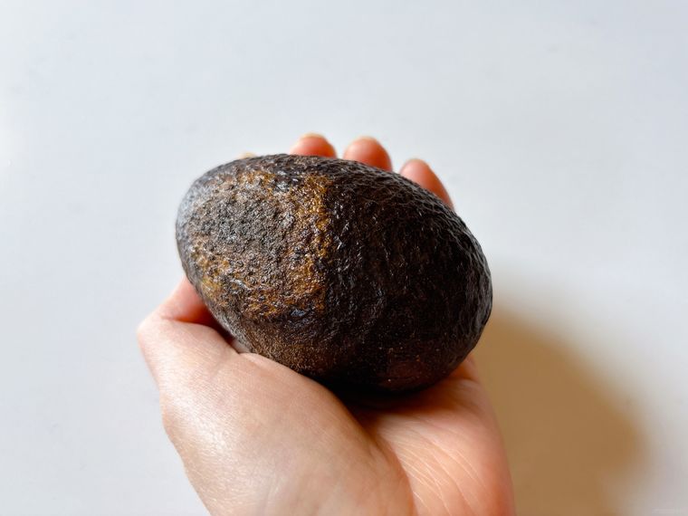 弾力のないアボカドを持った様子