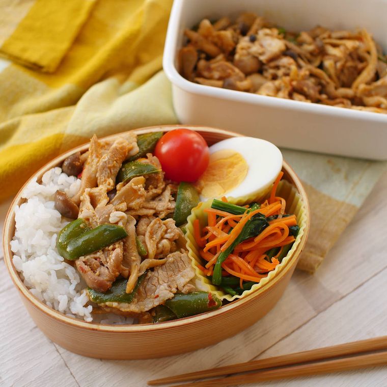 木製の弁当箱にごはんや回鍋肉が詰められている