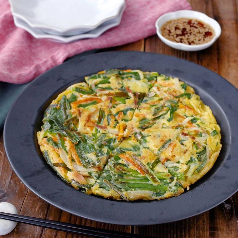 黒色の丸皿に盛られた米粉のニラチヂミ