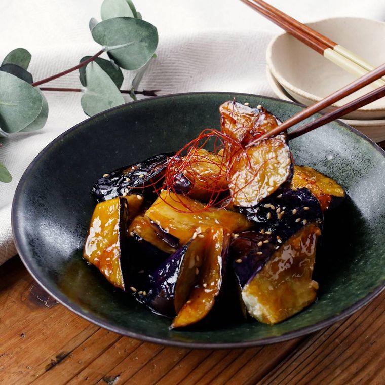 なすの甘酢炒めが黒い皿に盛り付けられているところ