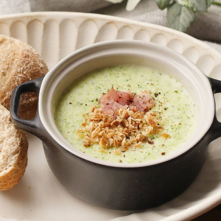 白いプレートの上の、黒い器に盛り付けたブロッコリーのポタージュ