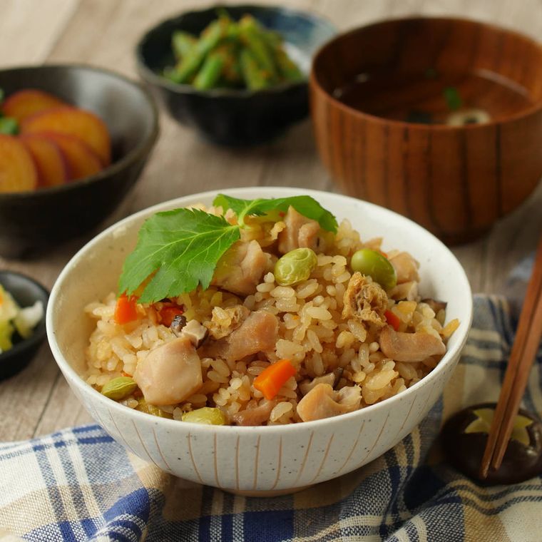 ベージュに茶色の線模様が入った茶碗い盛られた炊き込みご飯