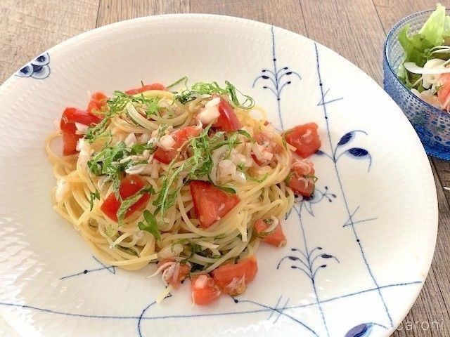 白地に柄入りの皿に盛られ、大葉をトッピングしたしらすとトマトの冷製パスタ
