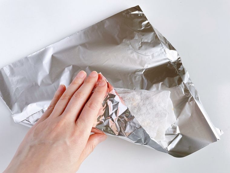 焼き芋を湿ったキッチンペーパーで包んでからアルミホイルで包む様子