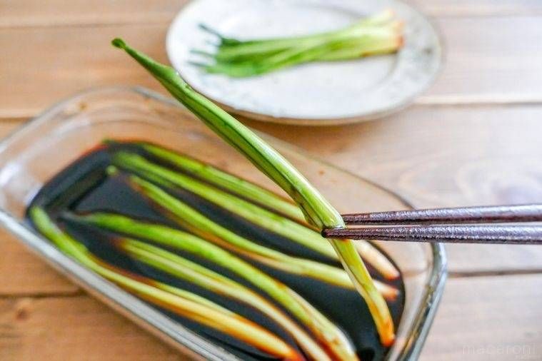 保存容器に入った行者にんにくのしょうゆ漬けを摘む様子