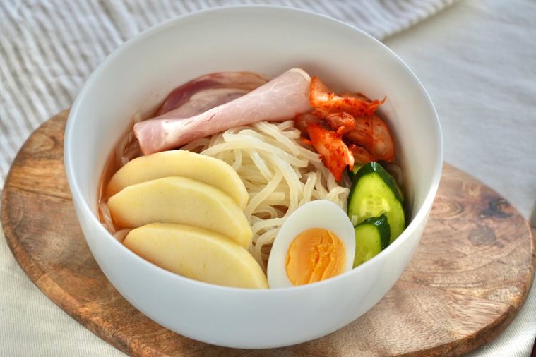 りんごや卵やきゅうりやキムチがトッピングされた盛岡冷麺と白い器