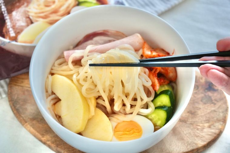 盛岡冷麺を黒い箸で持ち上げる様子