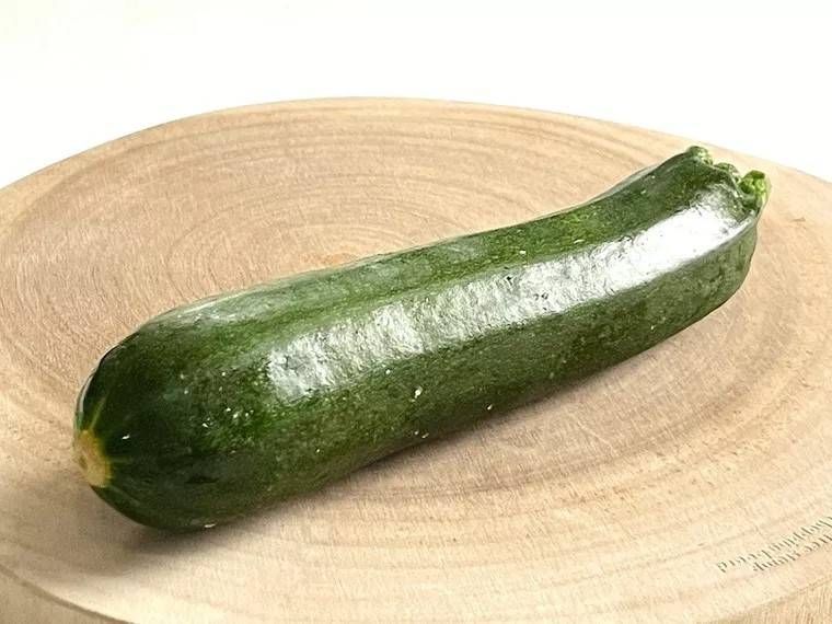 丸いまな板の上にズッキーニが1本置かれている