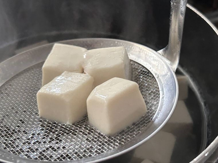 カットした絹豆腐を下ゆでして湯からすくい上げているところ