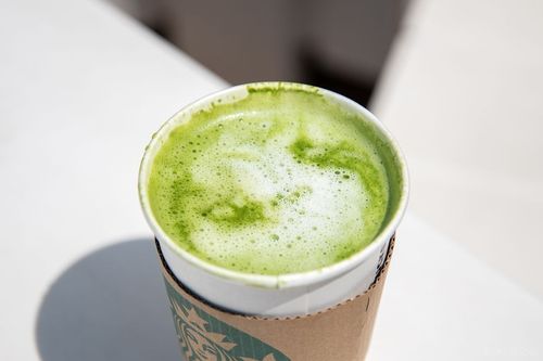 カスタマイズした抹茶 ティー ラテが白いテーブルに置かれている様子