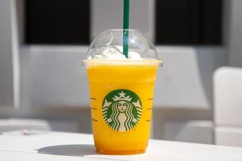 カスタマイズしたマンゴー パッション ティー フラペチーノが白いテーブルに置かれている様子
