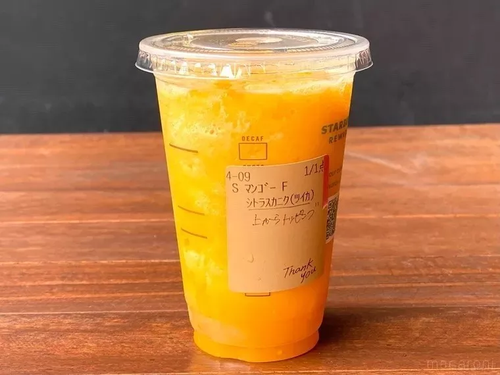 カスタマイズされたマンゴー パッション ティー フラペチーノがテーブルに置かれている