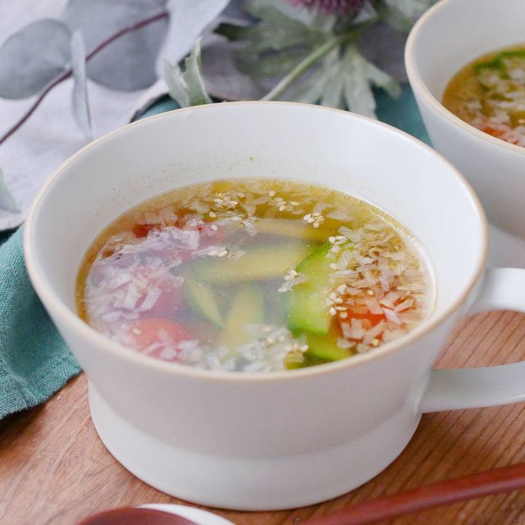 白いカップに盛りつけられたきゅうりとミニトマト、長ねぎのスープ