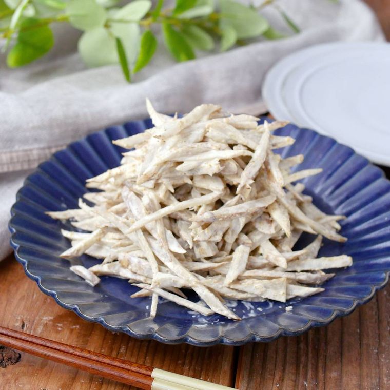 藍色の花びら形皿に盛りつけられているごぼうのごまマヨサラダ