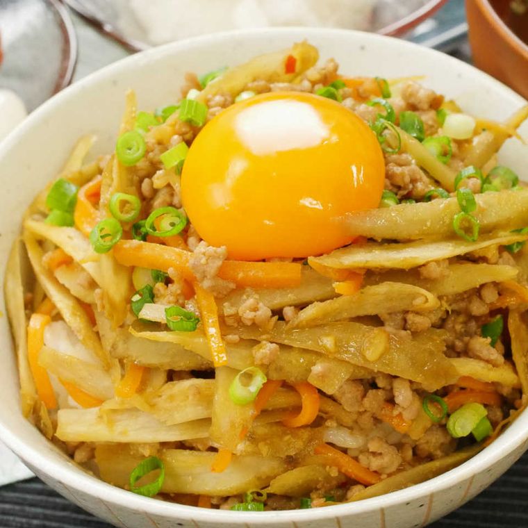 丼に盛られたご飯とピリ辛肉味噌きんぴらの上に卵黄がのせられた様子