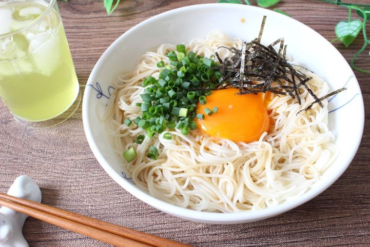 白いお皿に盛られた釜玉そうめんと、箸、お茶が並んでいる様子