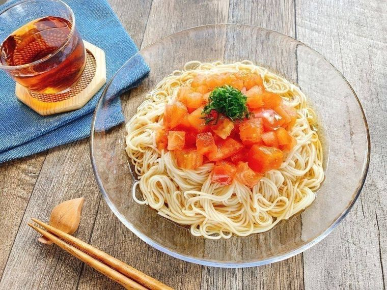 透明なガラス皿に盛られた、大葉がトッピングされているトマトそうめん