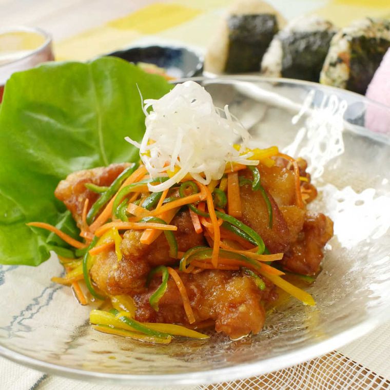 ガラス皿に盛りつけられている鶏の唐揚げとカラフル野菜のマリネ