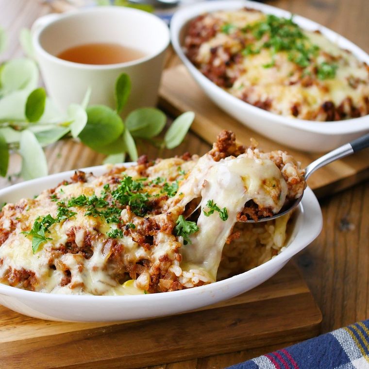 白いグラタン皿に盛られたミートソースドリアをスプーンですくっている様子