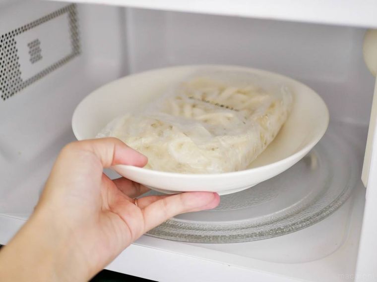 耐熱皿にのせた冷凍うどんを電子レンジに入れる様子