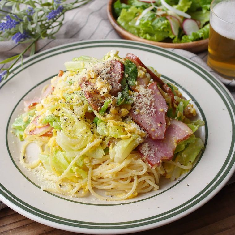 キャベツの卵パスタ、サラダ、ビールがテーブルに置かれている