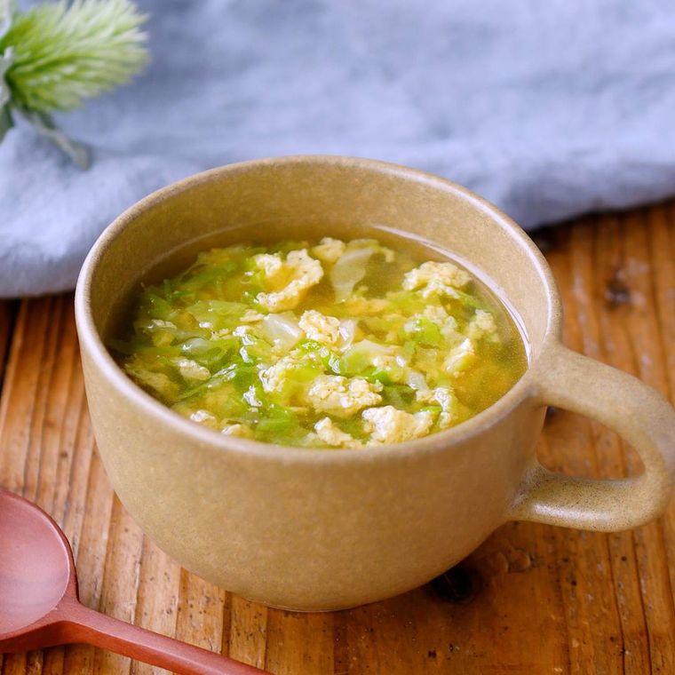 カップに入れられたキャベツと卵のスープにスプーンが添えられている