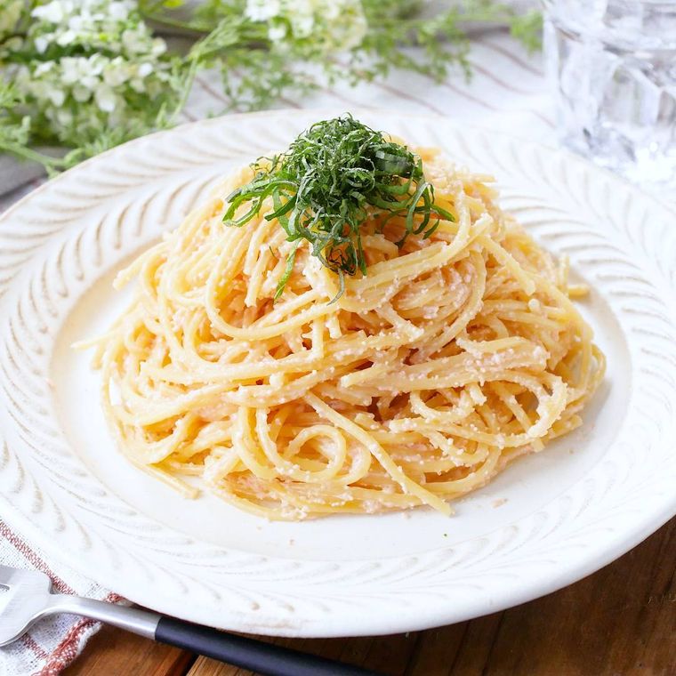 縁取りがある皿に盛りつけ大葉がトッピングされた明太クリームパスタ