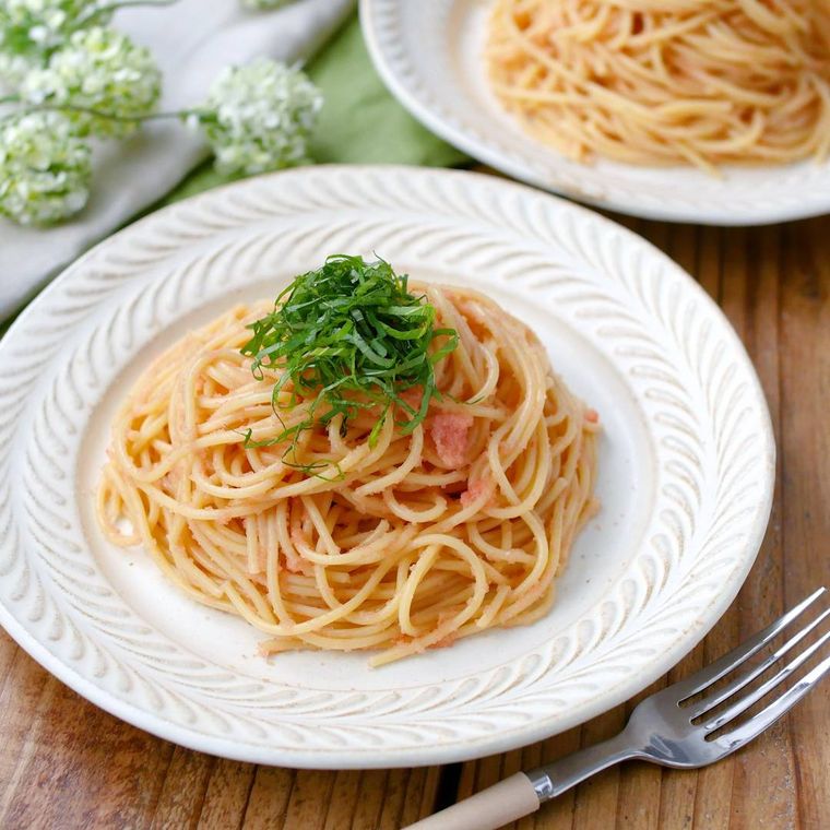 縁取りがある白い皿に盛りつけられた明太子と大葉のめんつゆパスタ